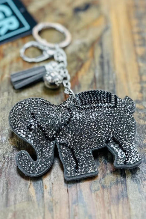 Silver elephant keychain with tassel on a wooden surface, featuring the brand 'GR'.