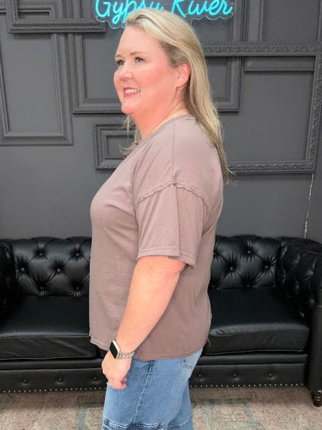 Woman standing in a room with a black leather couch and decorative elements.