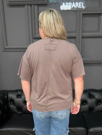 Person standing in front of a black leather sofa with a gray wall and decorative elements in the background.