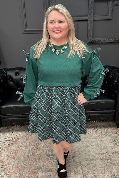 Woman in green top and patterned skirt standing in a store with Christmas decorations.