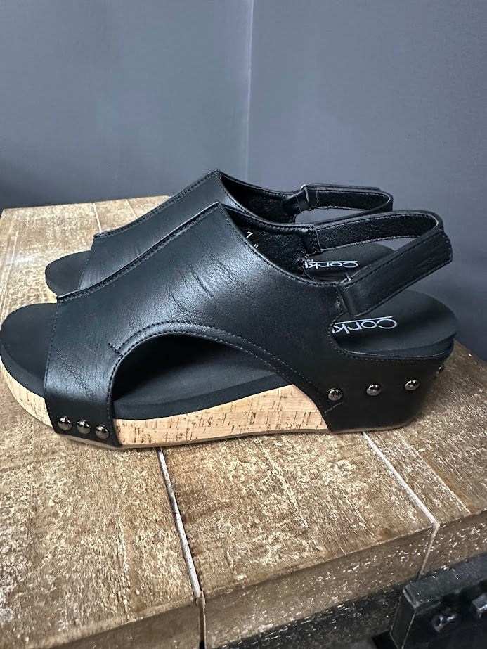 Black sandal with studded details on a wooden surface