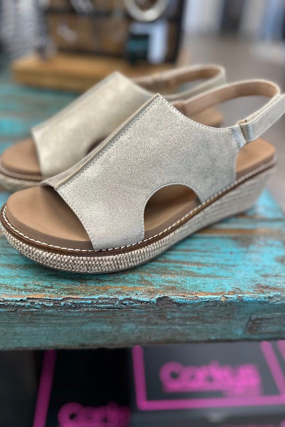 Silver sandal with brown sole on a blue wooden surface