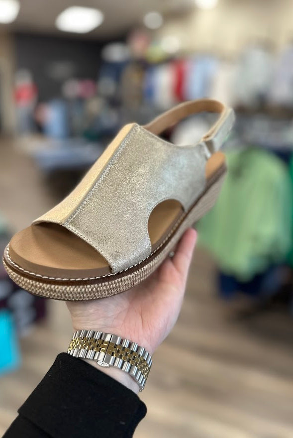 Hand holding a sandal with a blurred store interior background