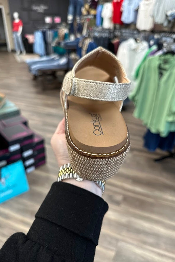 Gold sandal with rhinestone sole held in a clothing store.