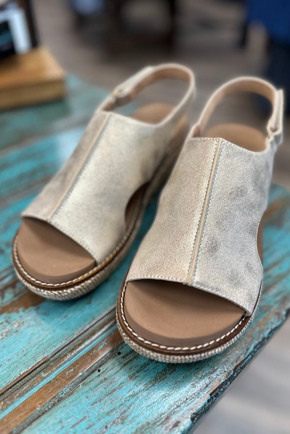 Pair of beige open-toe sandals on a wooden surface