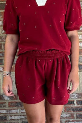 Woman wearing a red outfit with white collar against a brick wall