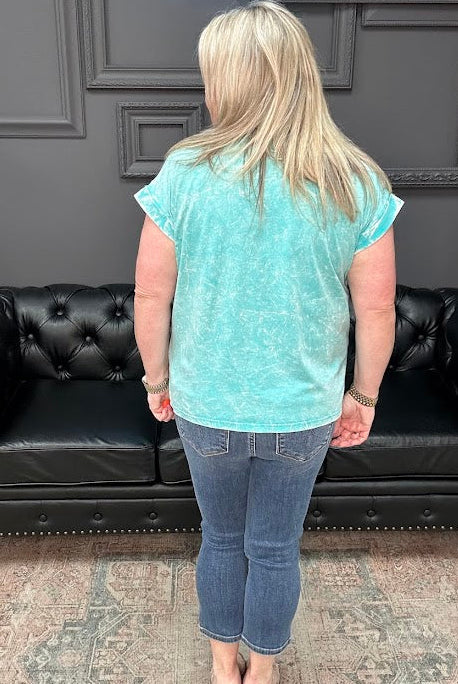 Person wearing a light blue t-shirt and jeans standing in front of a black leather couch.