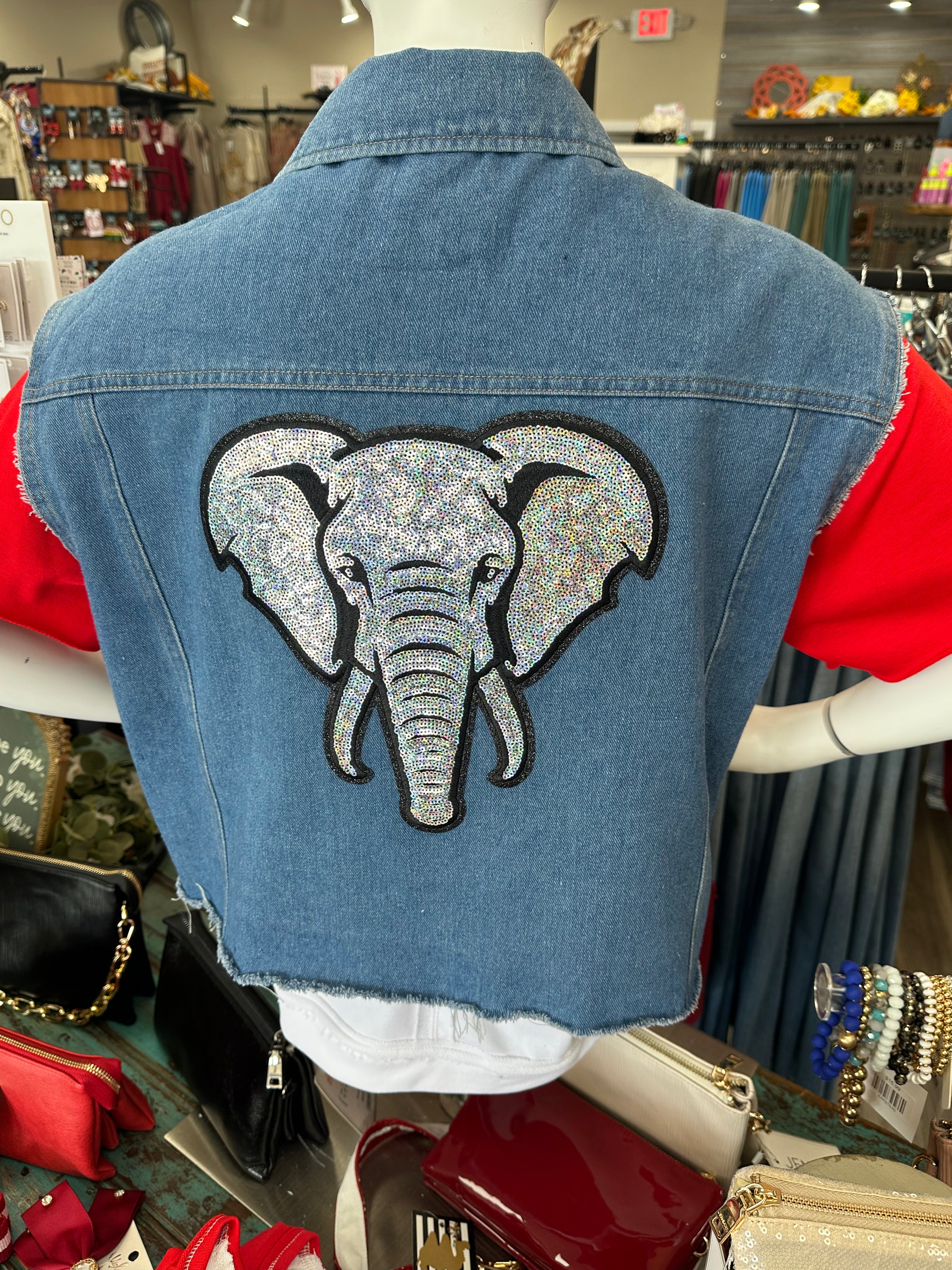 Denim jacket with an elephant patch on a mannequin in a store setting.