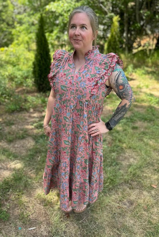 Woman in a floral dress standing outdoors in a garden