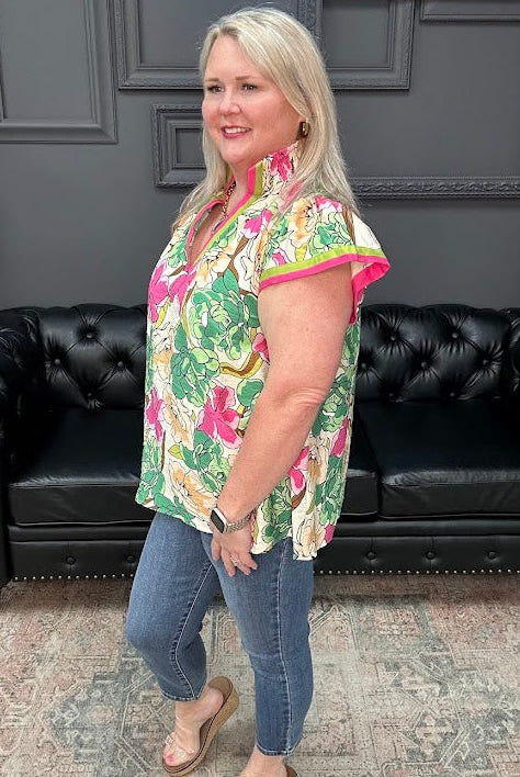 Woman wearing a floral shirt and jeans standing in front of a black leather couch.