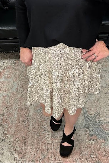 Woman in a black top and patterned skirt standing in a store with Christmas decorations.