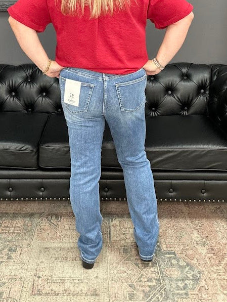 Person wearing blue jeans with a tag in front of a black leather couch.