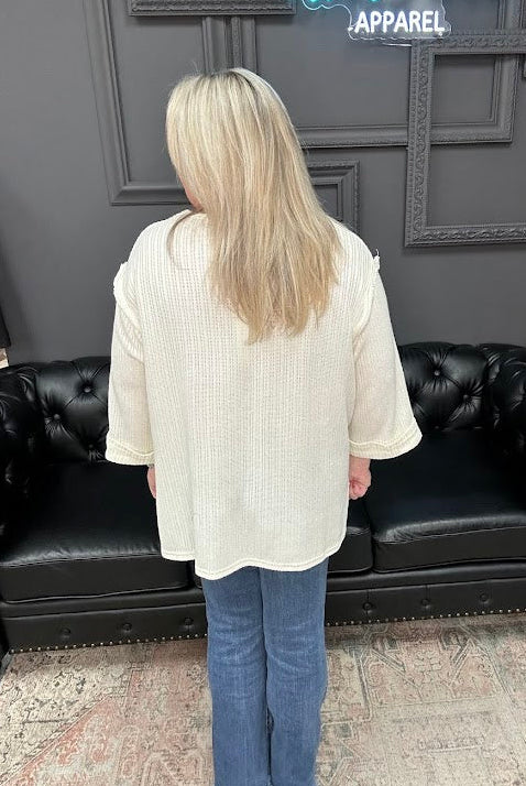 Person wearing a white shirt and blue jeans standing in front of a black leather couch with a Christmas tree in the background.