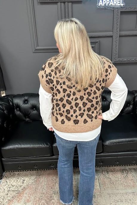 Person wearing a leopard print vest in front of a black couch with 'Gypsy River Apparel' sign.