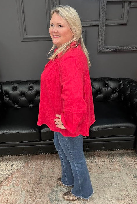 Woman in a red top and blue jeans standing in front of a black leather couch with 'Gypsy River Apparel' branding.