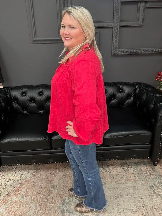 Woman in a red top and blue jeans standing in front of a black leather couch with 'Gypsy River Apparel' branding.