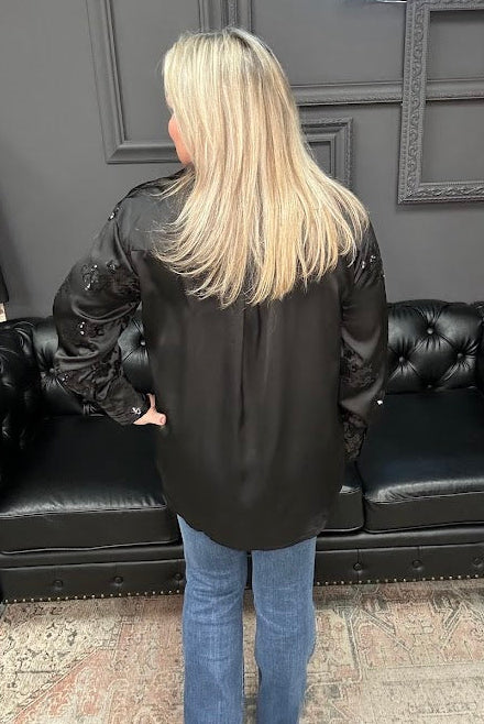 Person wearing a black leather jacket standing in front of a black leather couch with 'Gypsy River Apparel' branding.
