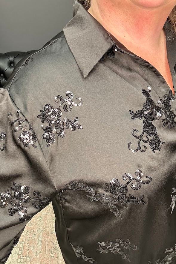 Close-up of a dark gray shirt with floral sequin embellishments on a blurred background