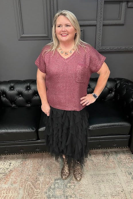 Woman standing in front of a black leather couch with a Christmas tree and 'Gypsy River Apparel' sign in the background.