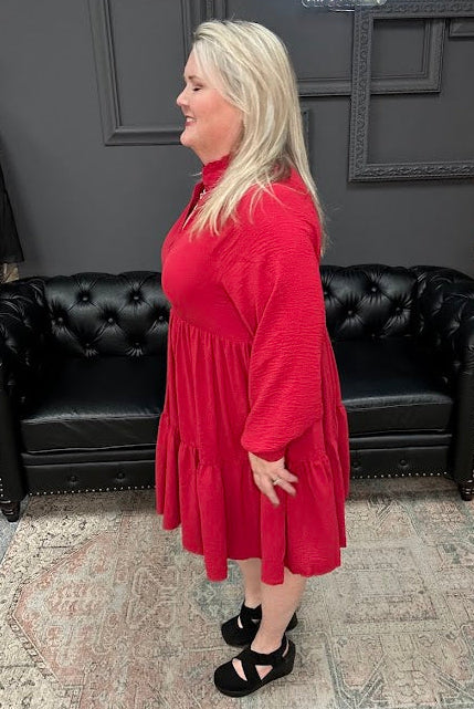 Woman in a red dress standing in a store with a Christmas tree and 'Gypsy River Apparel' sign.