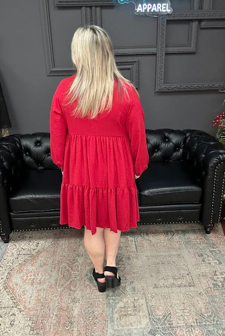 Woman in a red dress standing in front of a black leather couch and Christmas tree in a store.