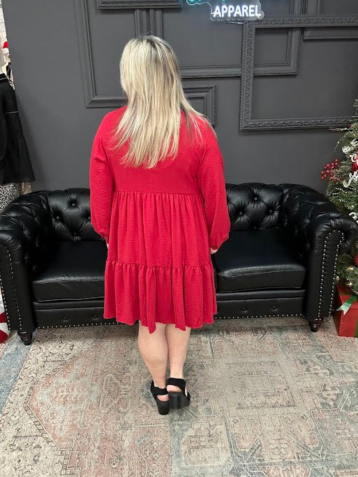 Woman in a red dress standing in front of a black leather couch and Christmas tree in a store.