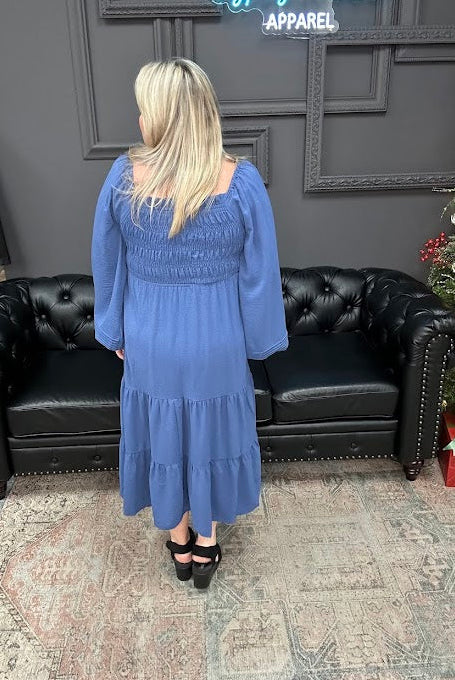 Woman in a blue dress standing in a store with a Christmas tree and 'Gypsy River Apparel' sign.