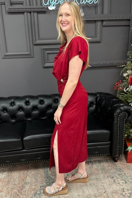 Woman in a red dress standing in a room with a black couch and Christmas tree.