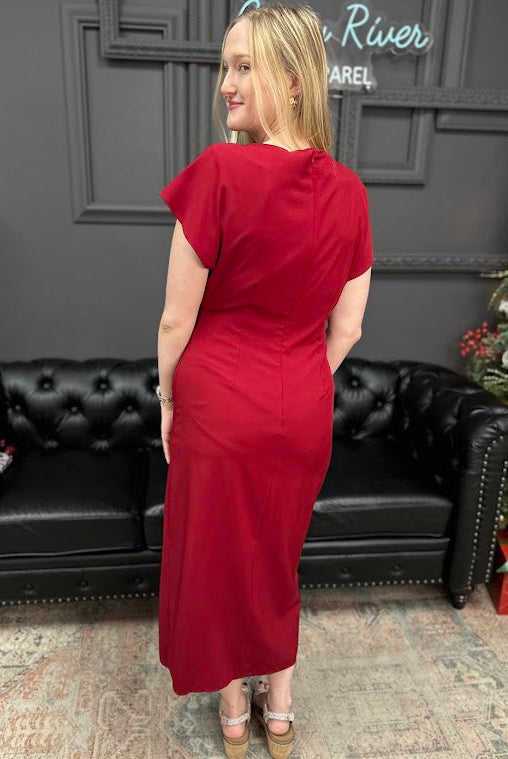 Woman in a red dress standing in a room with a black couch and Christmas decorations.