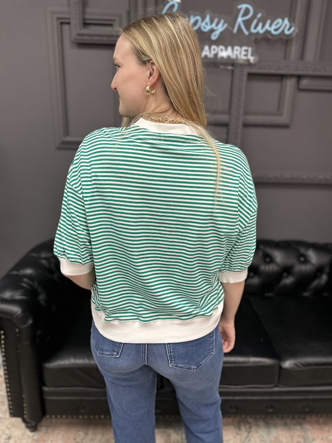 Person wearing a green and white striped shirt with a blurred background