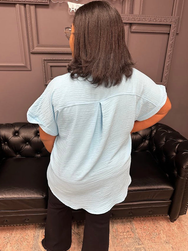 Person wearing a light blue shirt sitting on a brown leather couch with a brown wall in the background.