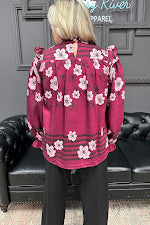 Person wearing a pink floral jacket sitting on a black leather couch.