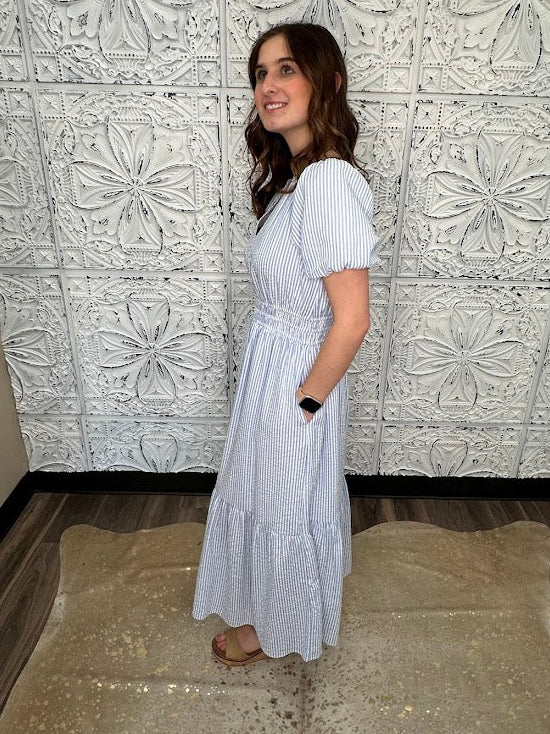 Woman in a white dress standing in front of a decorative tiled wall.
