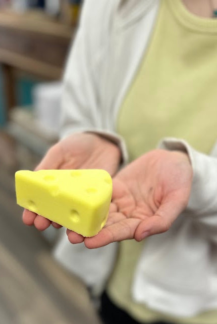 Person holding a yellow bar of soap in an indoor setting