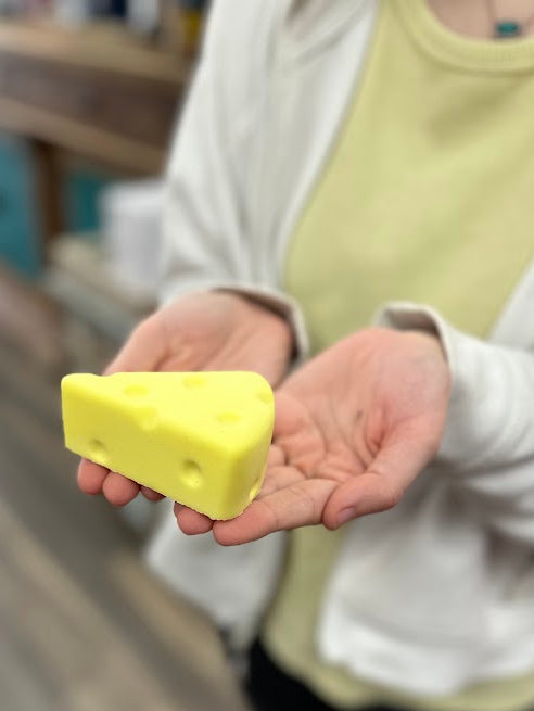 Person holding a yellow bar of soap in an indoor setting