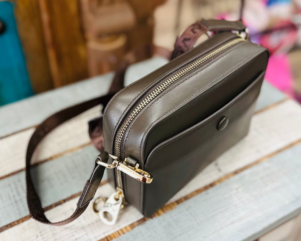 Black leather handbag with gold zipper on a wooden surface