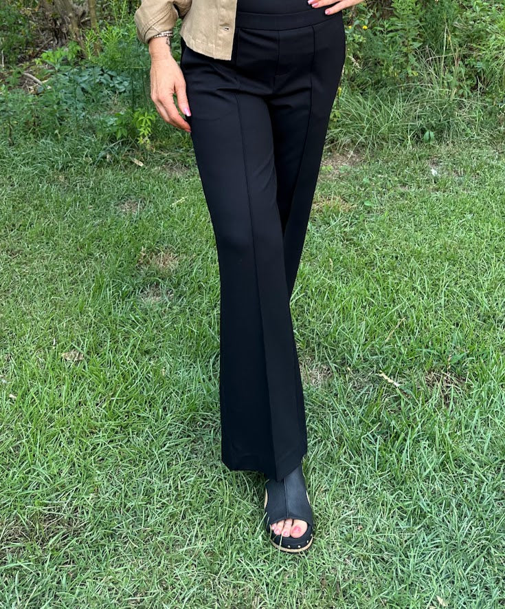Person wearing black flared pants standing on grass
