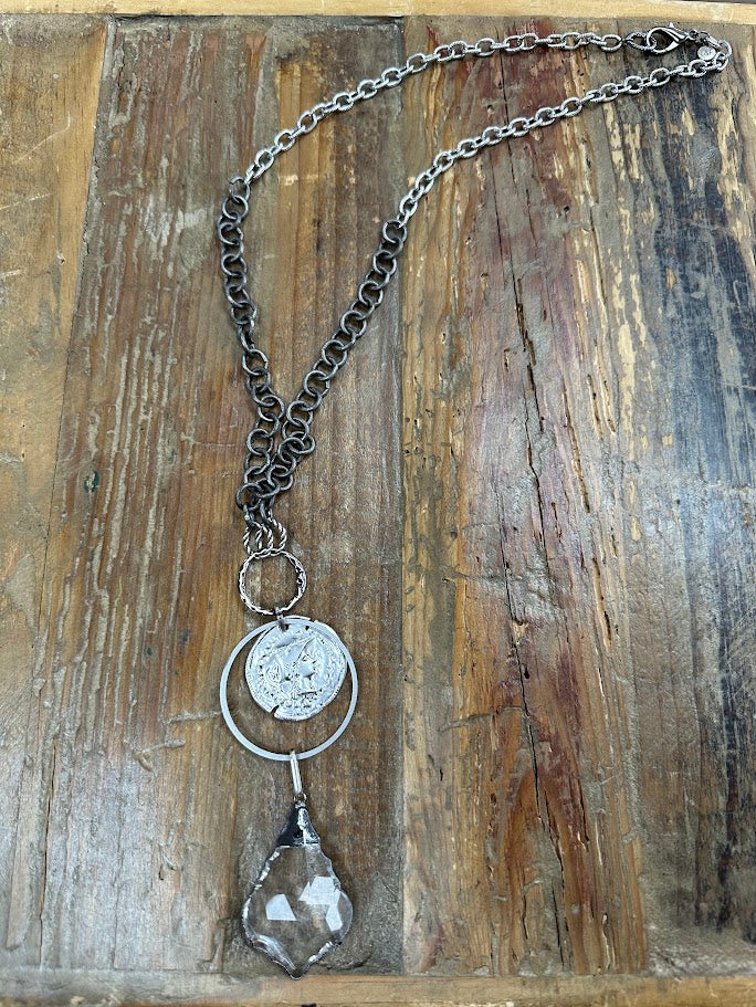 Mixed metal statement necklace with coin detail and smoky crystal drop. Bold, layered, and effortlessly eye-catching.