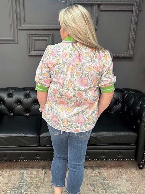 Person wearing a floral shirt and jeans standing in front of a black leather couch.