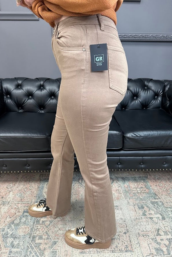 Person wearing beige pants with a brand tag in a room with a black leather couch.