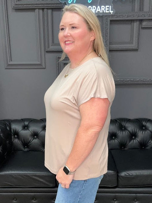 Woman standing in a room with a black leather couch and decorative wall.