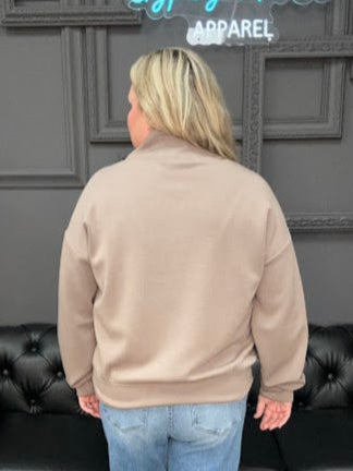 Person standing in front of a black leather couch with a gray wall and decorative elements in the background.
