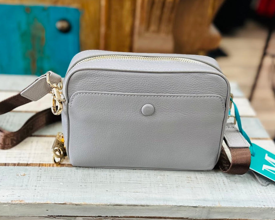Gray crossbody bag on a wooden surface with a visible brand tag.
