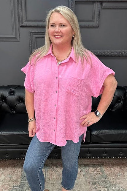 Woman wearing a pink shirt and blue jeans standing in front of a black leather couch.