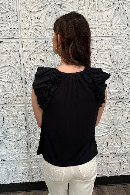 Liverpool black sleeveless blouse with ruffle trim and tie front neckline on model