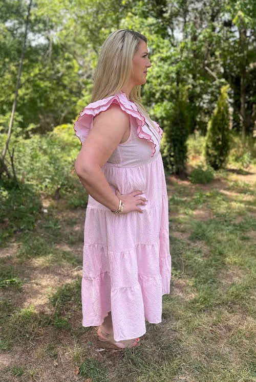Woman in a pink dress standing outdoors in a natural setting