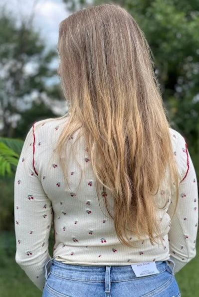 Person wearing a white blouse with floral patterns and blue jeans in an outdoor setting.