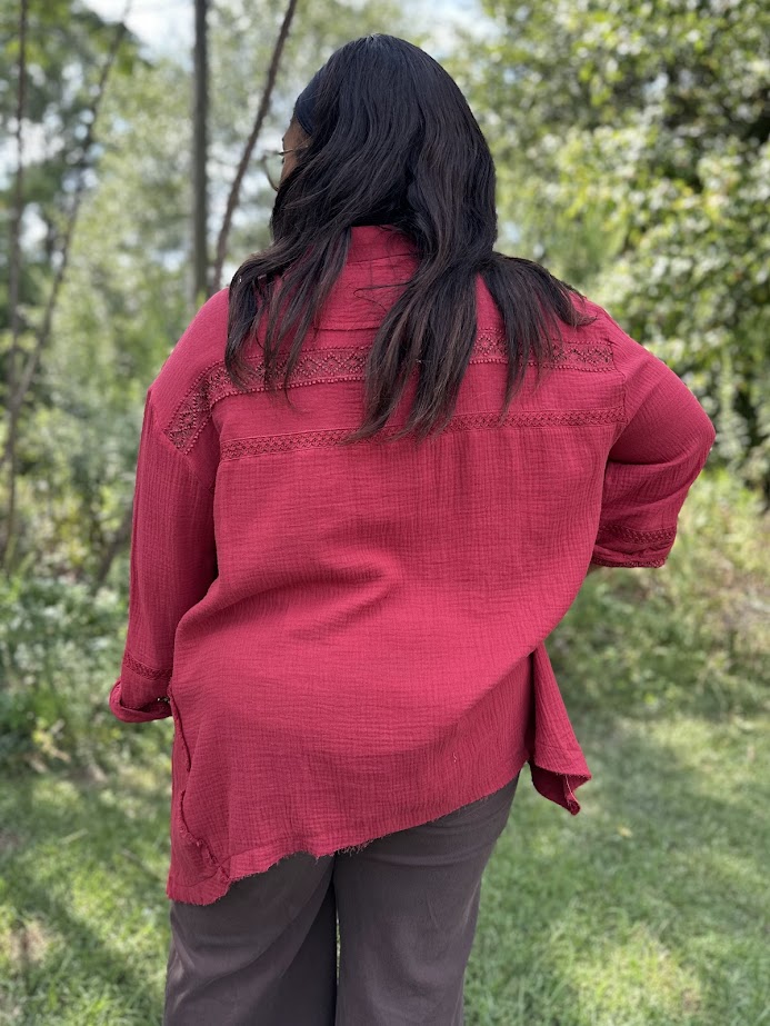 Person wearing a red shirt with intricate patterns outdoors