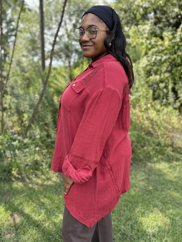 Woman wearing a red shirt and glasses standing in a forested area