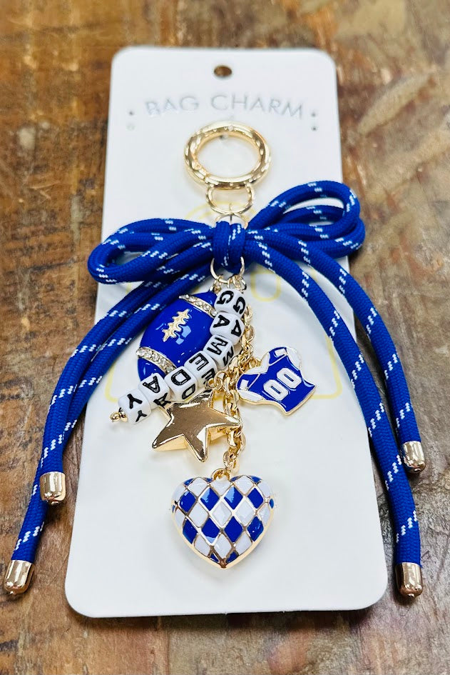 Blue and gold gameday bow keychain with decorative elements on a wooden surface